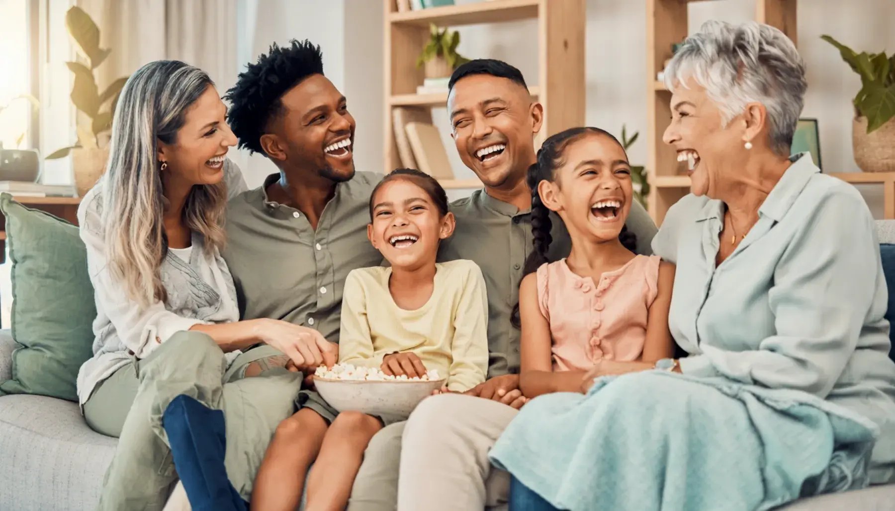 Three generations of a family laughing together on the couch